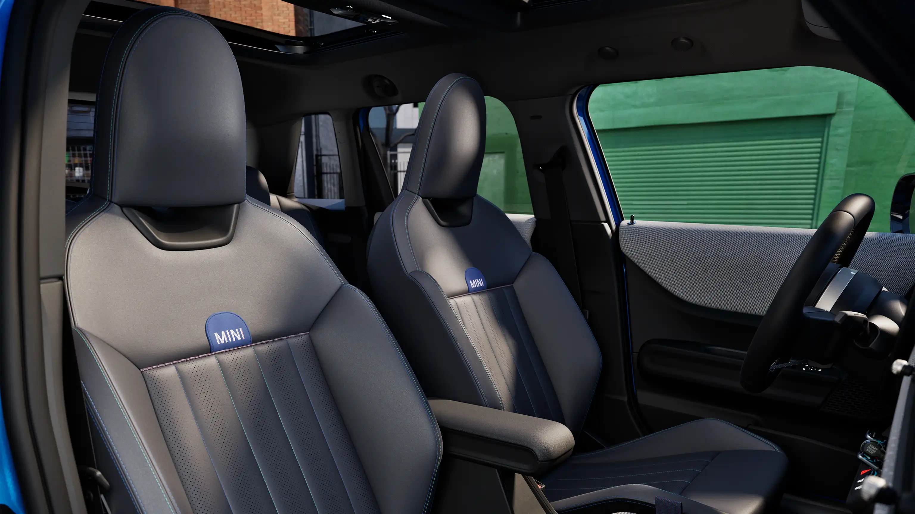 Interior perspective of the MINI Cooper 5-Door is showing the dashboard, steering wheel, round display, panorama glassroof and back of the frontseats.