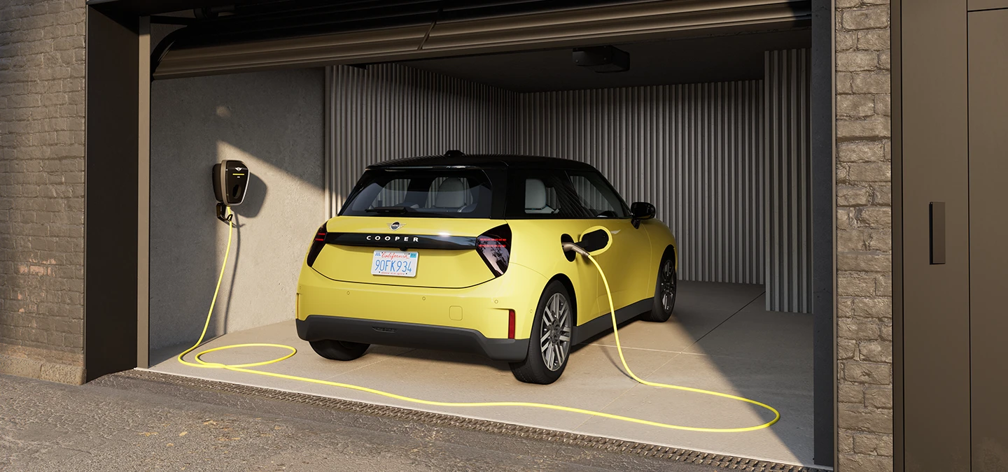 Rear view of an all-electric MINI Cooper in Sunnyside Yellow while charging in a garage. 