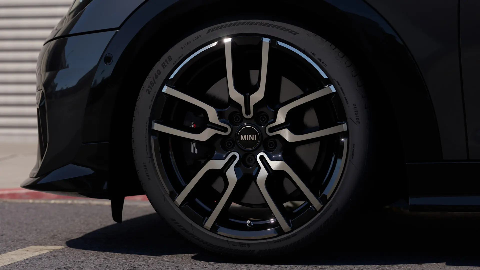 Close-up of the JCW Lap Spoke alloy wheel showing its distinctive open spoke design structure in Jet Black finish. 